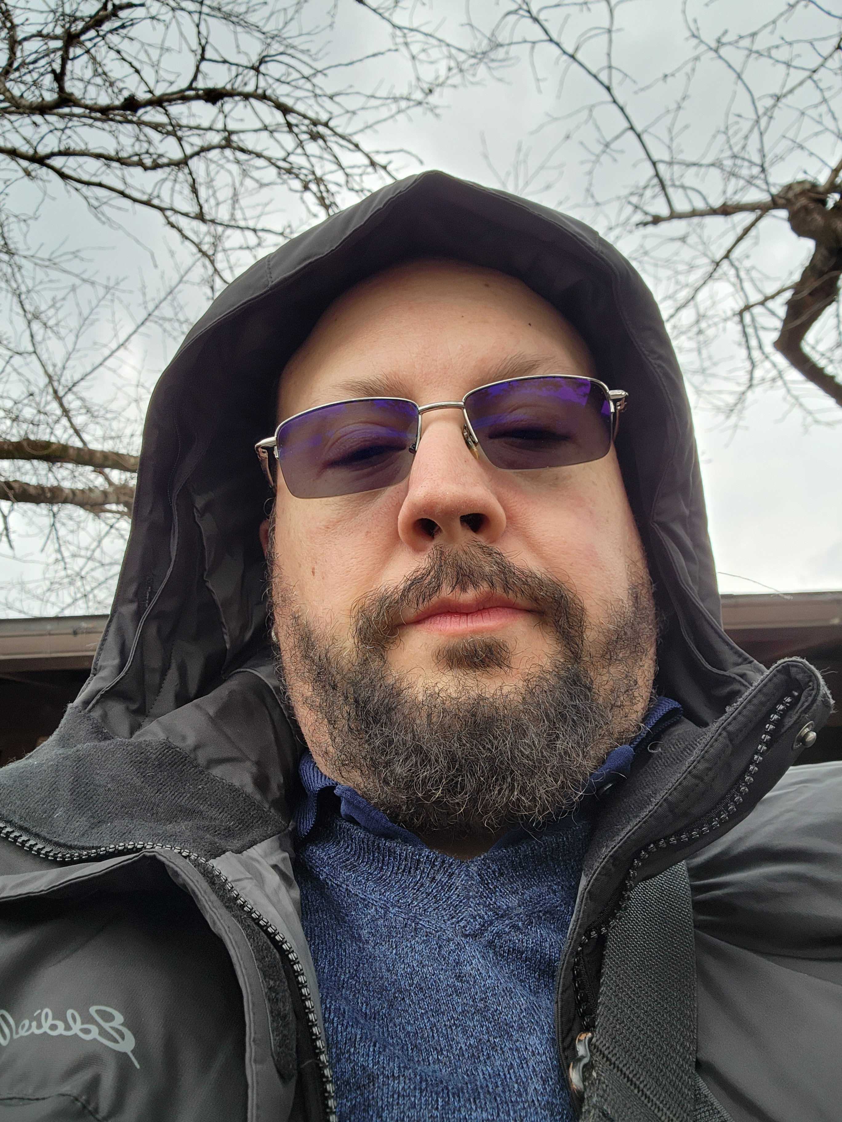Stephen in hood and dark glasses, bare winter trees - moody and mysterious